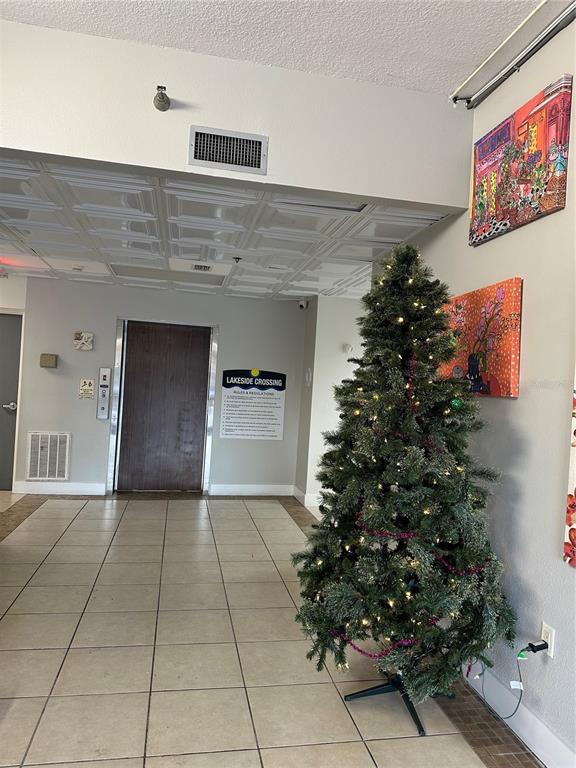 A waiting area features a leather sofa, a large abstract painting, and a red elevator door — 701 S MADISON AVENUE UNIT 410, CLEARWATER, FL