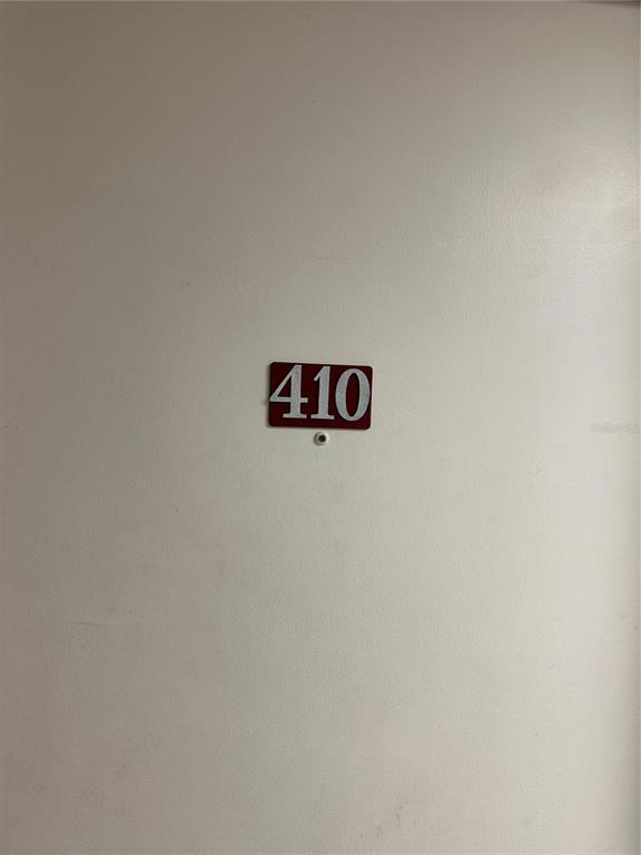 A white door features a red rectangular sign with the number 410 and a peephole — 701 S MADISON AVENUE UNIT 410, CLEARWATER, FL