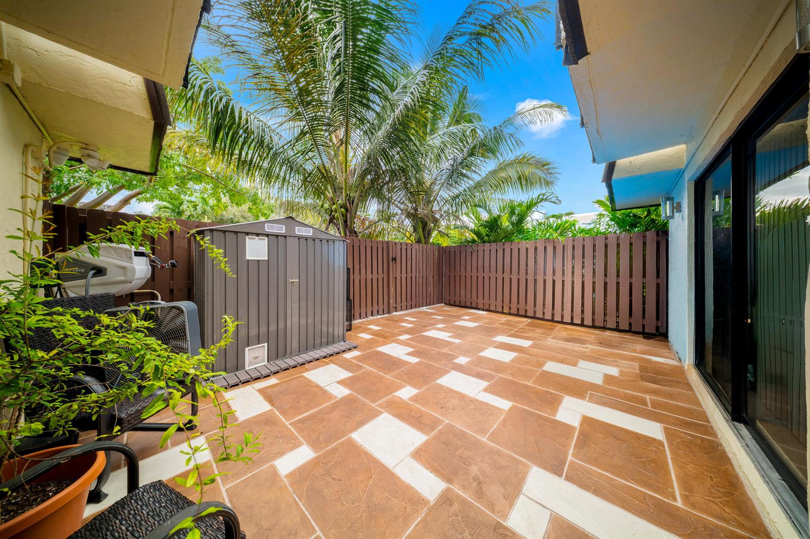 A paved patio features a storage shed, a privacy fence, and a palm tree — 1524 Forest Lakes Circle, West Palm Beach FL 33406, WEST PALM BEACH, FL