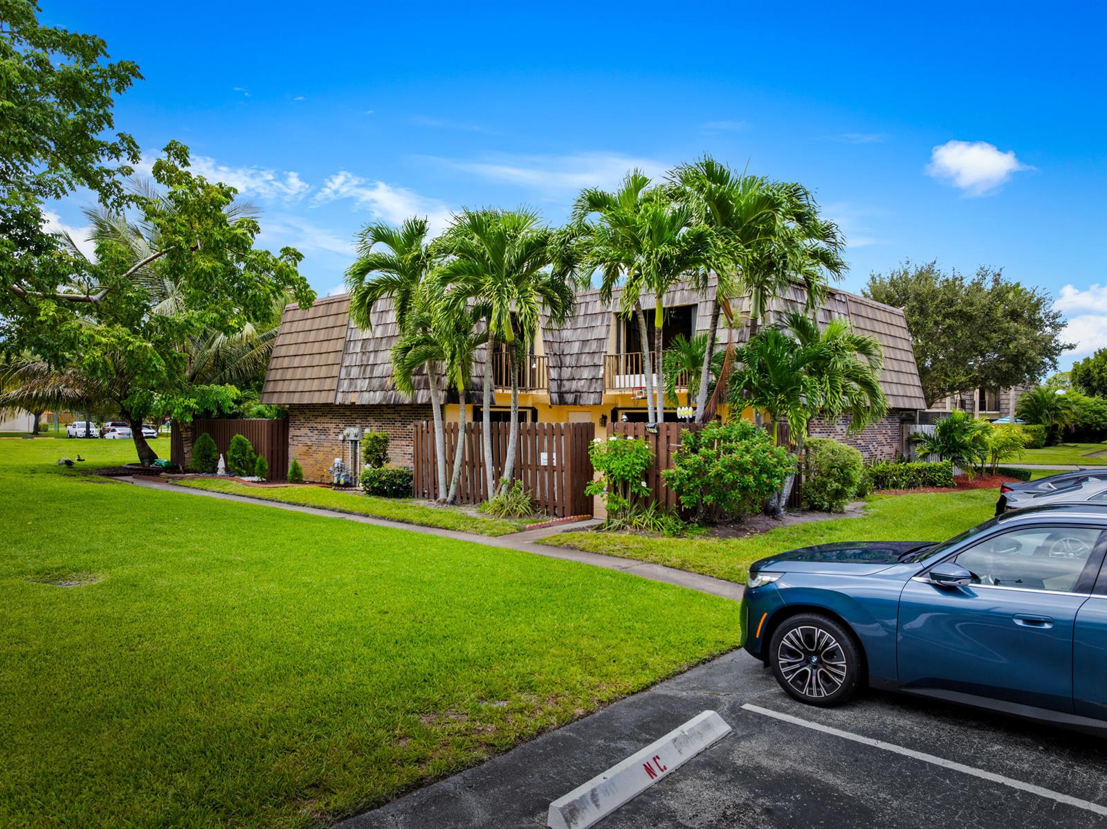 A two-story building with a shingled mansard roof, palm trees, and a wooden privacy fence — 1524 Forest Lakes Circle, West Palm Beach FL 33406, WEST PALM BEACH, FL