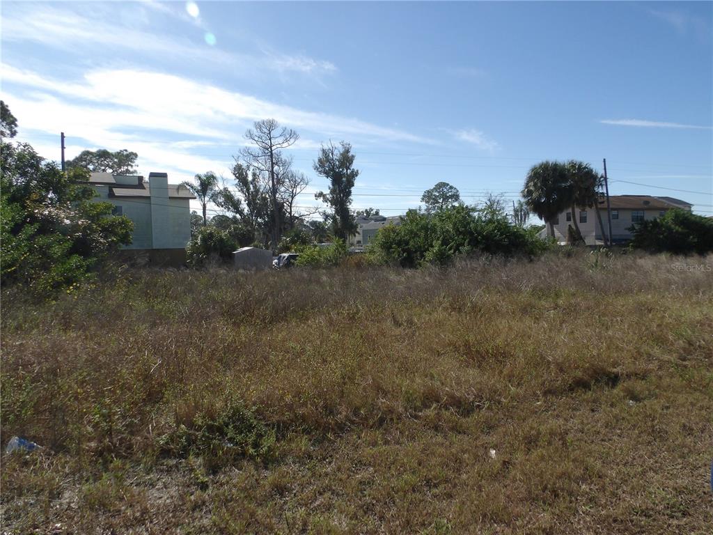 A vacant, grass-covered lot with trees and neighboring houses in the background — 523 DORIC COURT, TARPON SPRINGS, FL