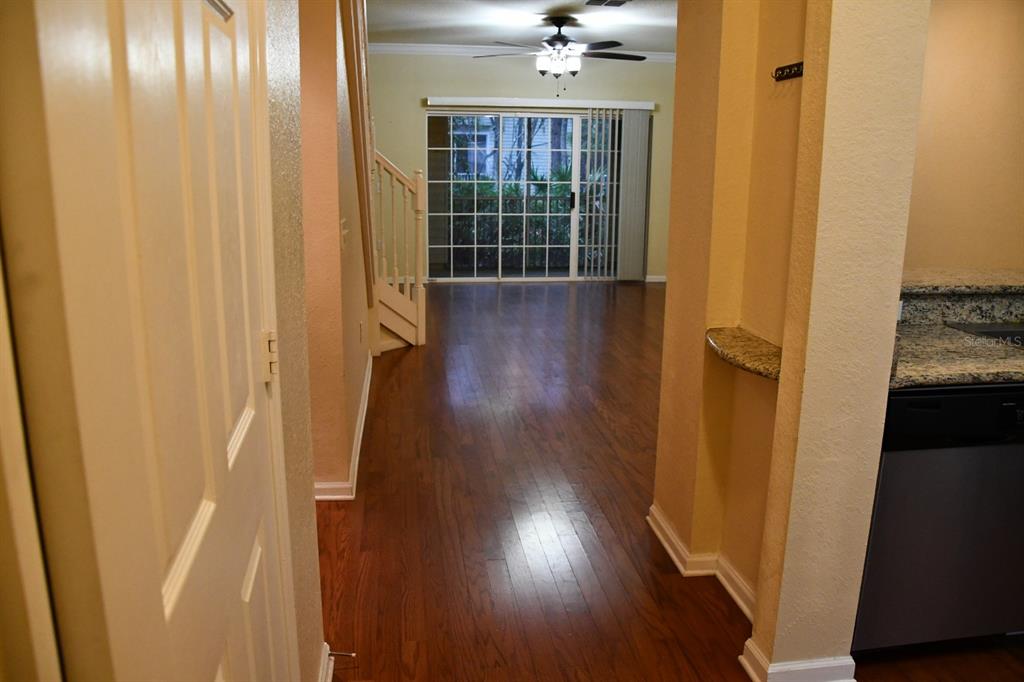 A view from a kitchen looking toward a living area with hardwood floors and sliding doors — 5062 NW 44TH LANE UNIT 107, GAINESVILLE, FL