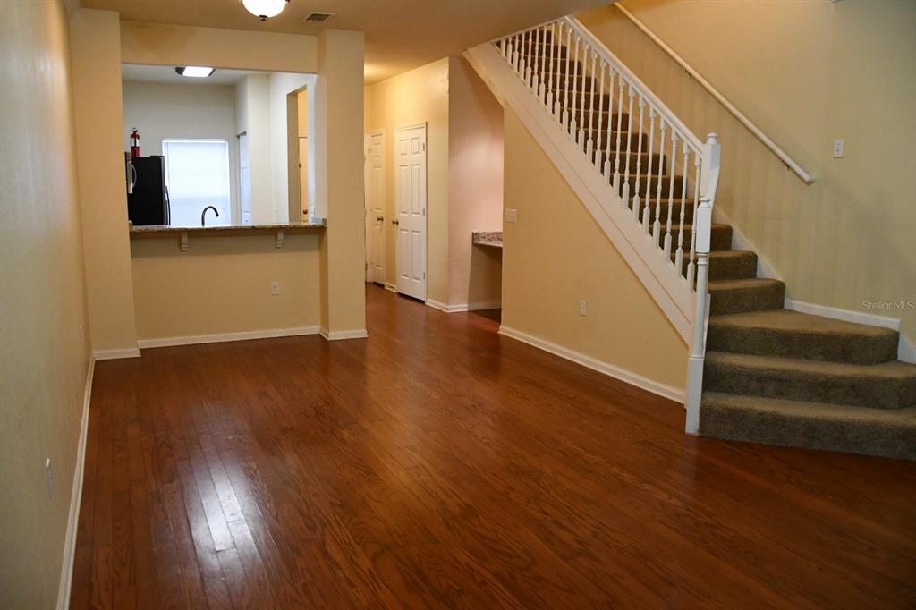 A living area with hardwood floors features a staircase and a kitchen pass-through window — 5062 NW 44TH LANE UNIT 107, GAINESVILLE, FL