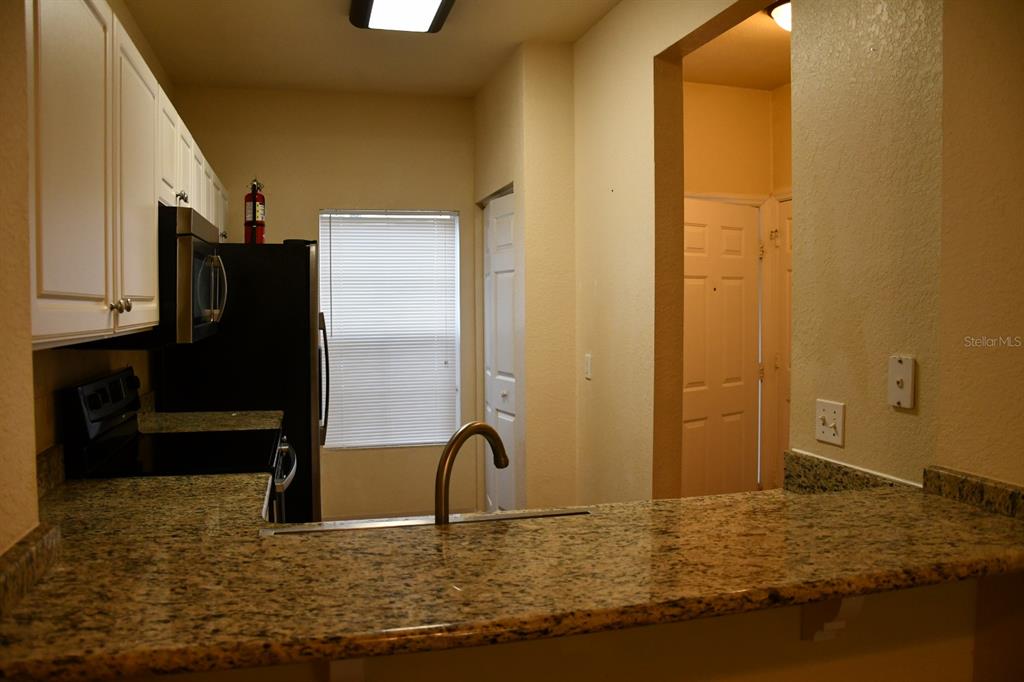 A kitchen with white cabinets, granite countertops, a black refrigerator, and a breakfast bar — 5062 NW 44TH LANE UNIT 107, GAINESVILLE, FL