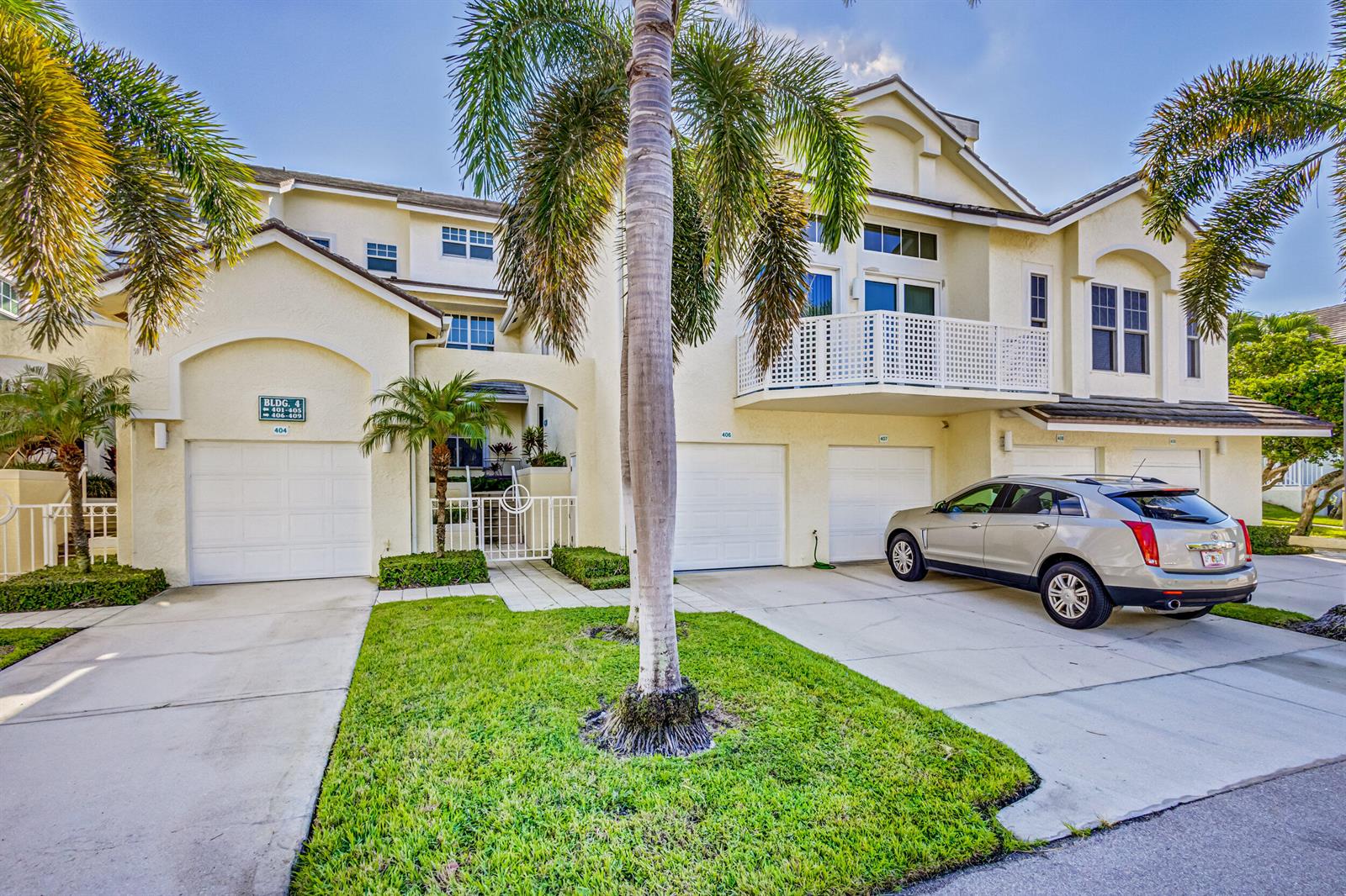 A multi-story residential building with garages, a palm tree, and a parked SUV — 406 Mainsail Circle, Jupiter FL 33477, JUPITER, FL