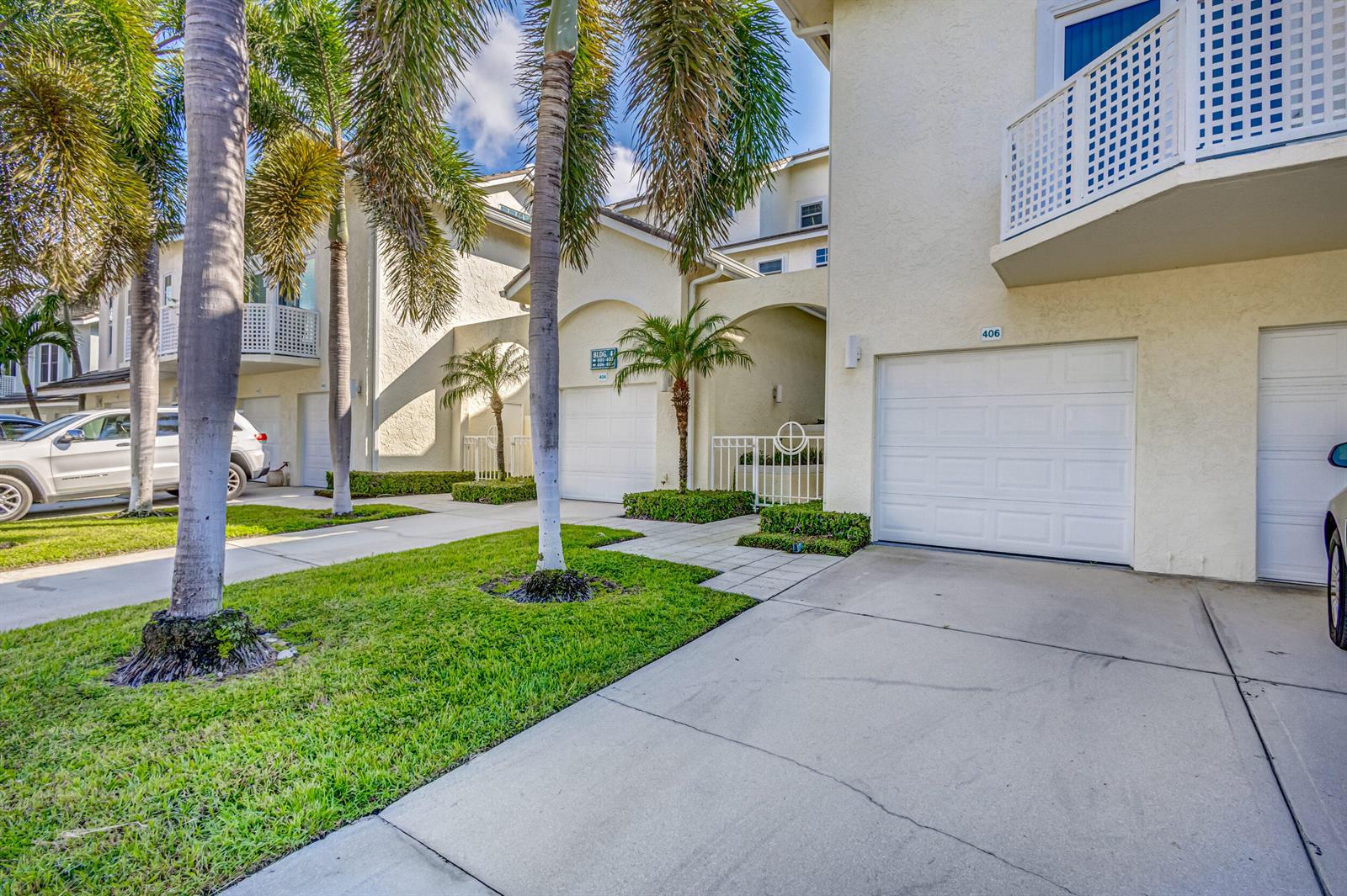Exterior view of a multi-story residential building with garages, palm trees, and paved driveways — 406 Mainsail Circle, Jupiter FL 33477, JUPITER, FL