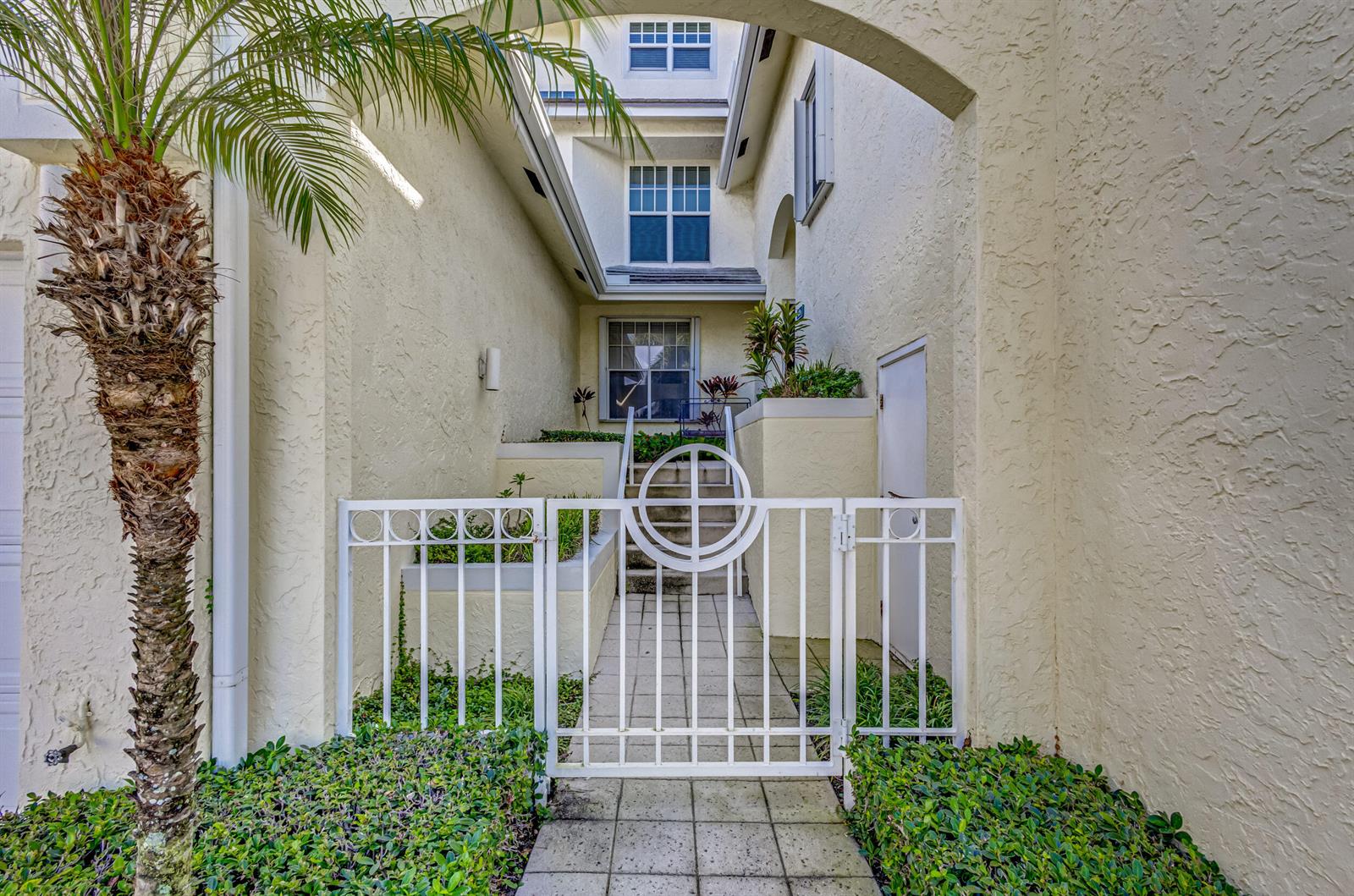 A gated walkway leads to a set of stairs at the entrance of a stucco home — 406 Mainsail Circle, Jupiter FL 33477, JUPITER, FL