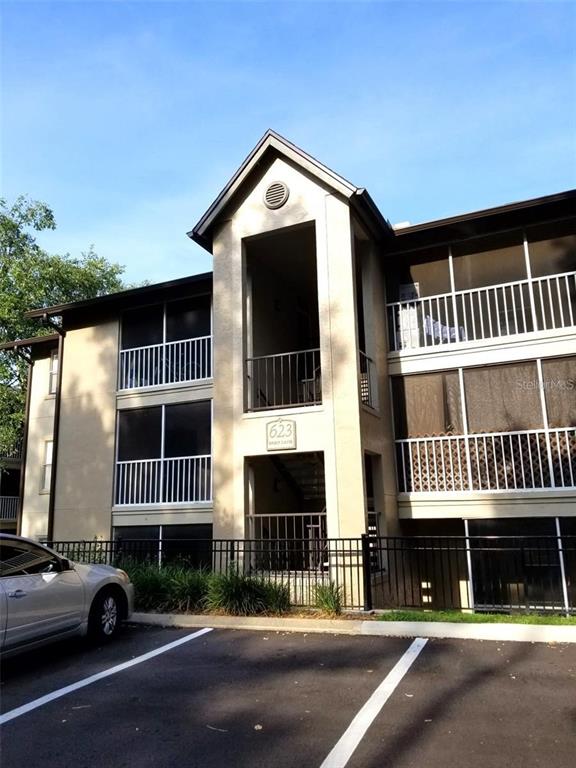 A three-story apartment building exterior features screened balconies and a parking lot in front — 623 DORY LANE UNIT 306, ALTAMONTE SPRINGS, FL