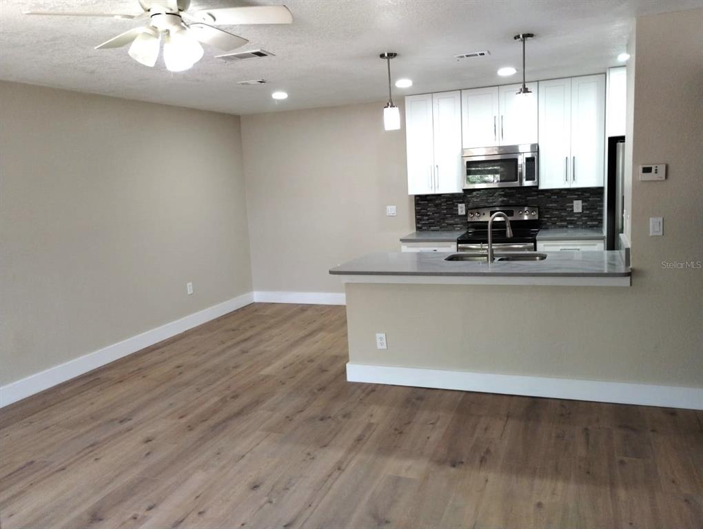A kitchen with white cabinets and a gray island overlooks an open living area — 623 DORY LANE UNIT 306, ALTAMONTE SPRINGS, FL