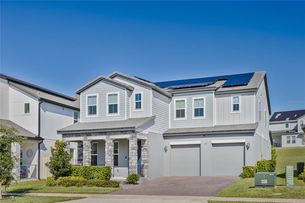 A two-story suburban house features a stone-accented porch, a two-car garage, and rooftop solar panels — 5150 CITRUS LEAF BOULEVARD, WINTER GARDEN, FL
