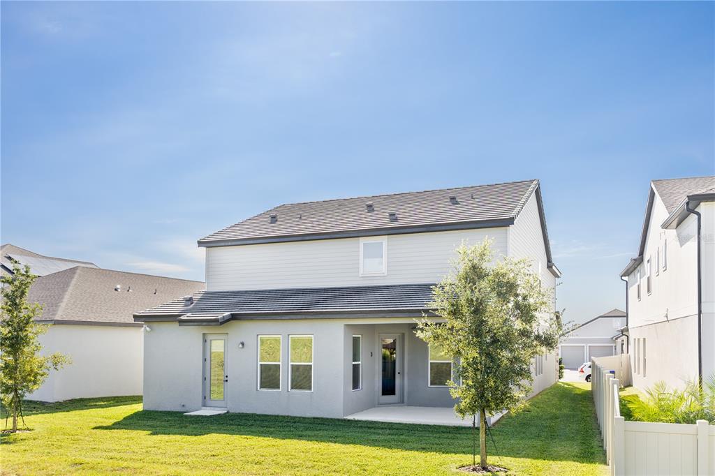 The rear exterior of a two-story house features light-colored siding, a patio, and a lawn — 5150 CITRUS LEAF BOULEVARD, WINTER GARDEN, FL