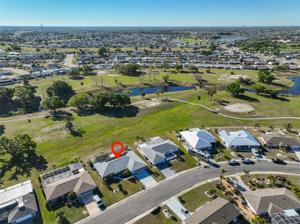 An aerial view shows a residential neighborhood with a marked house overlooking a golf course — 672 ALLEGHENY DRIVE, SUN CITY CENTER, FL