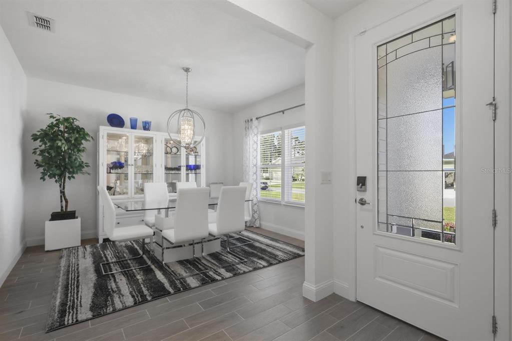 A dining room with a glass table, white chairs, and a patterned rug near an entryway — 2110 RAGLAN CIRCLE, ORMOND BEACH, FL