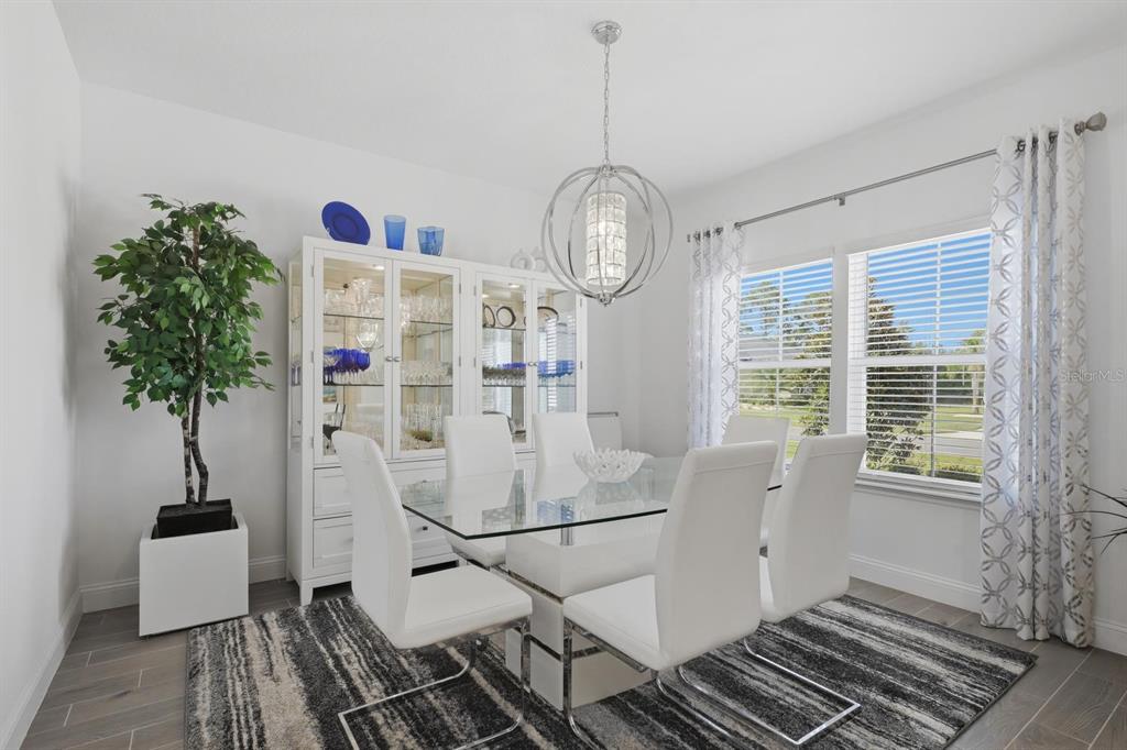 A dining room features a glass-topped table, white chairs, a china cabinet, and a chandelier — 2110 RAGLAN CIRCLE, ORMOND BEACH, FL