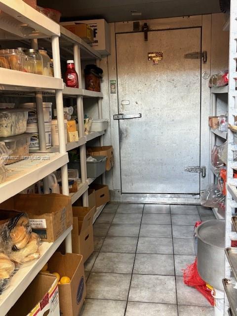 A walk-in cooler door is at the end of a storage room with metal shelving — 163rd, North Miami Beach FL 33162, NORTH MIAMI BEACH, FL