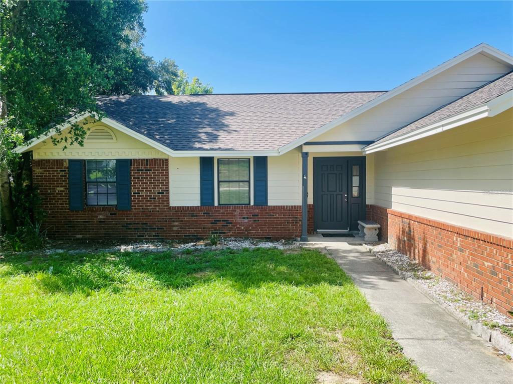 A single-story house with a brick and siding exterior, blue shutters, and a dark door — 6914 THOUSAND OAKS ROAD, ORLANDO, FL