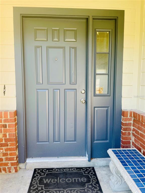 A dark blue front door with a side window sits between two brick pillars — 6914 THOUSAND OAKS ROAD, ORLANDO, FL