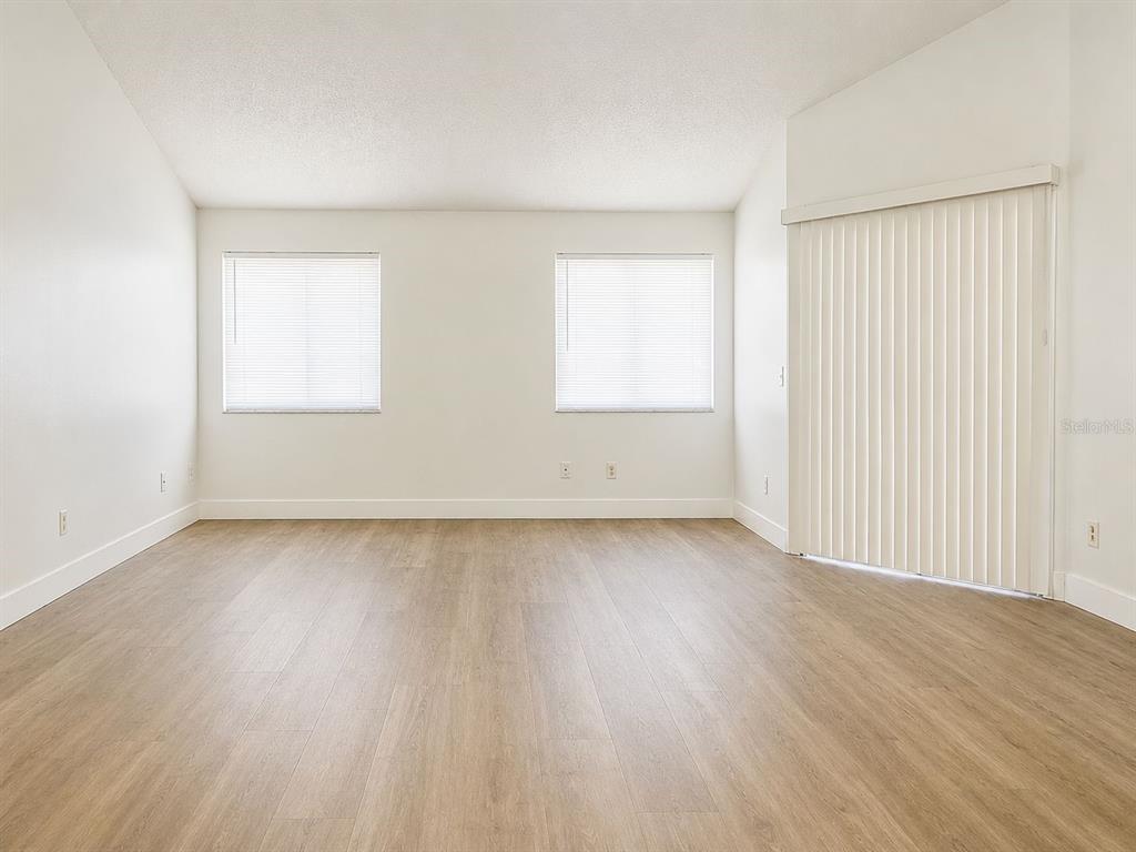 An empty room features light wood-look flooring, white walls, two windows, and vertical blinds — 6914 THOUSAND OAKS ROAD, ORLANDO, FL