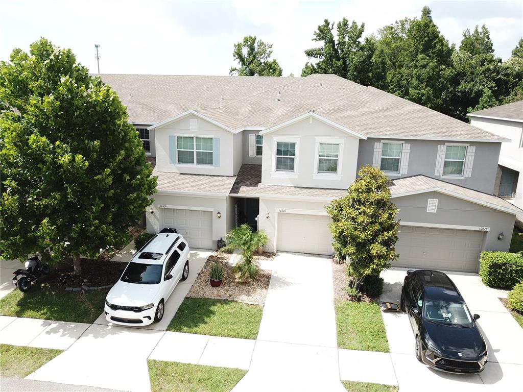 An aerial view shows a multi-unit residential building with three garages and two parked cars — 10676 LAKE MONTAUK DRIVE, RIVERVIEW, FL