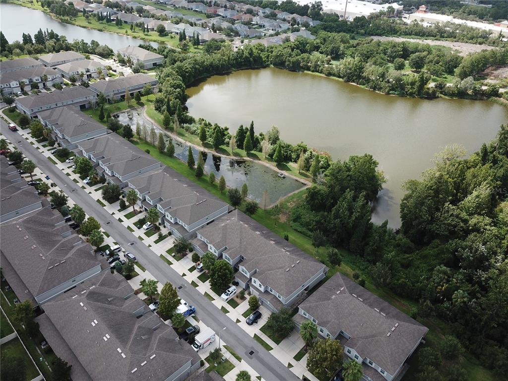 An aerial view shows a residential neighborhood with townhomes situated next to a large pond — 10676 LAKE MONTAUK DRIVE, RIVERVIEW, FL