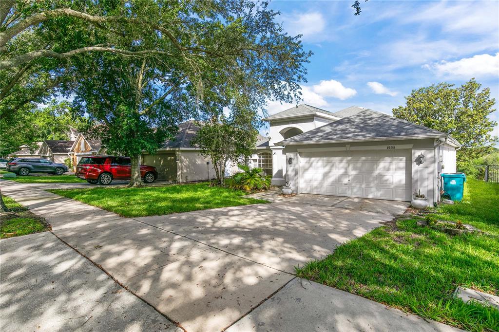 A suburban house with a two-car garage, concrete driveway, and large trees in the yard — 1935 WESTPOINTE CIRCLE, ORLANDO, FL