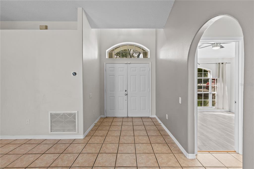 An entryway with tiled floors, a double front door, and an arched doorway to another room — 1935 WESTPOINTE CIRCLE, ORLANDO, FL