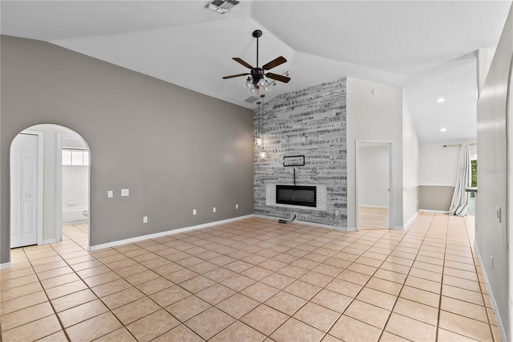 A living room with tile floors, a vaulted ceiling, and a fireplace with wood-look paneling — 1935 WESTPOINTE CIRCLE, ORLANDO, FL