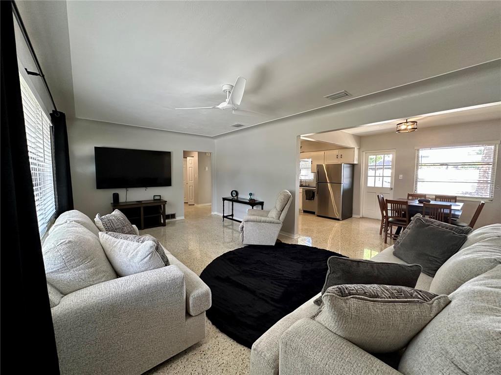 A living room with light-colored sofas, a black circular rug, and an open-concept kitchen — 4917 99TH STREET N, ST PETERSBURG, FL