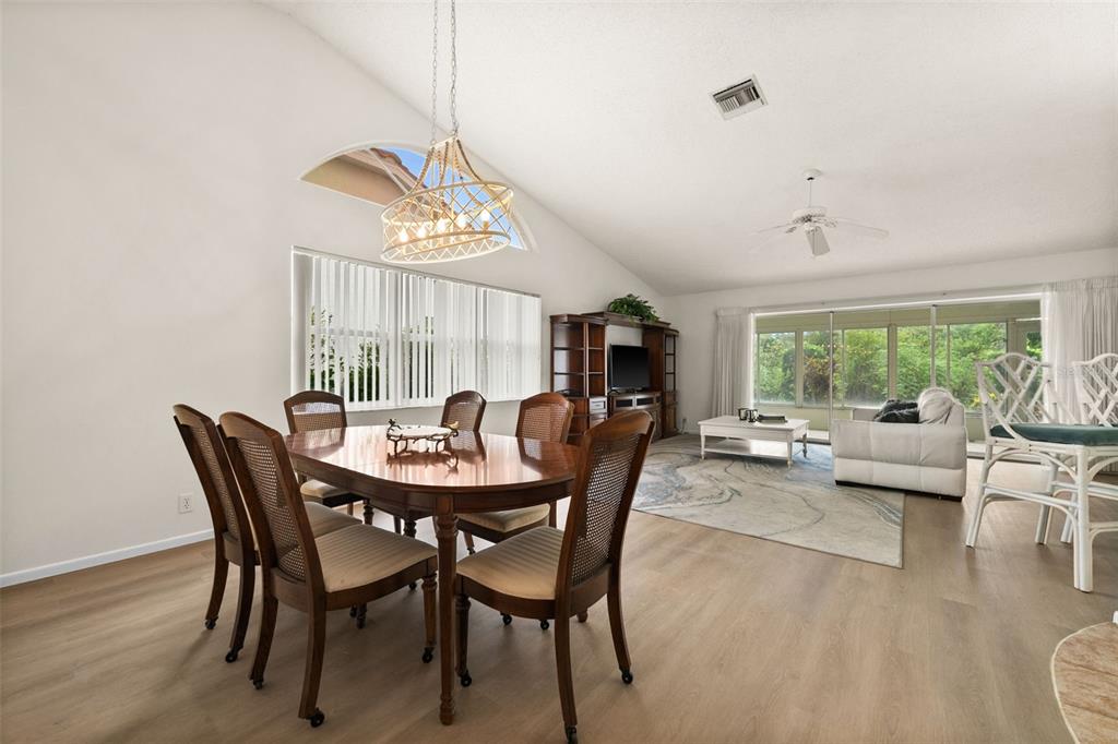 A dining area with a wooden table and chairs sits adjacent to a living room — 4825 TAMARACK TRAIL, VENICE, FL