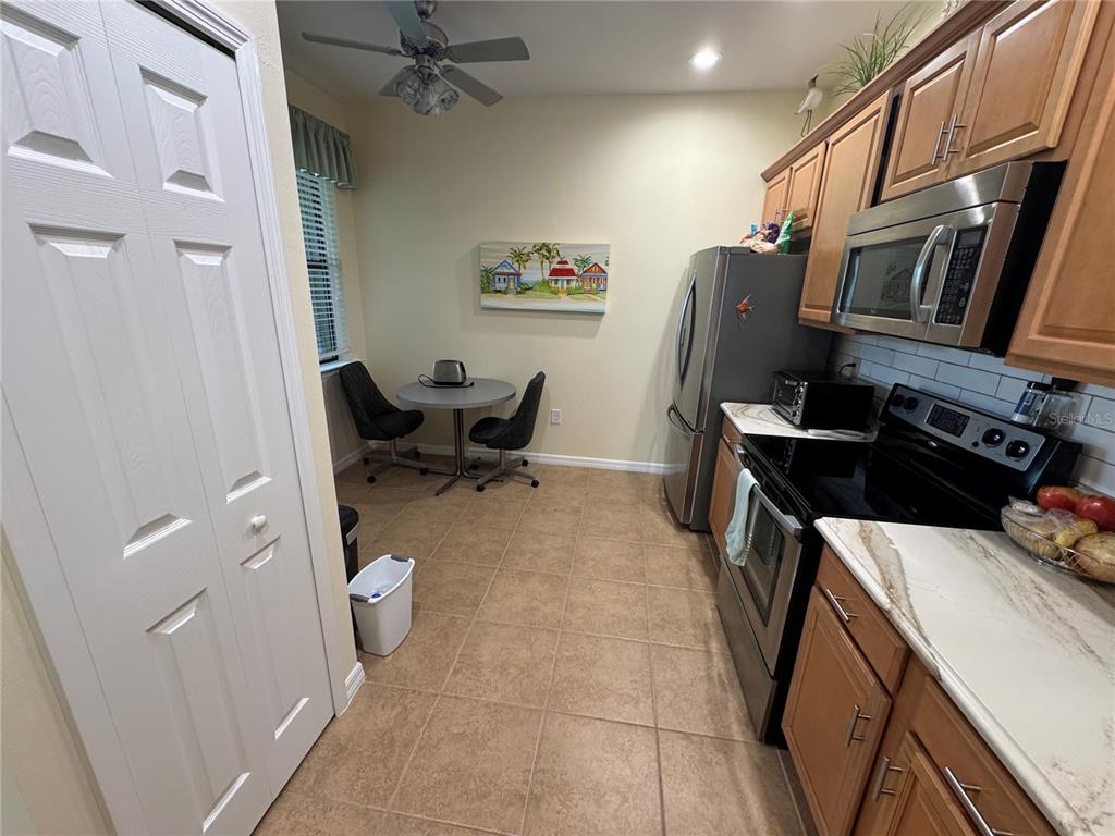 A kitchen features wood cabinets, stainless steel appliances, tile flooring, and a small dining area — 20096 PEZZANA DRIVE, VENICE, FL