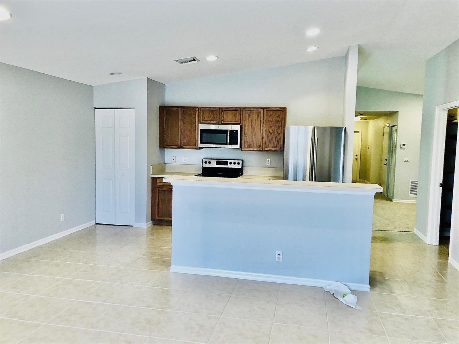A kitchen with wood cabinets, stainless steel appliances, and a breakfast bar overlooks a room — 4801 SE Graham Drive, Stuart FL 34997, STUART, FL
