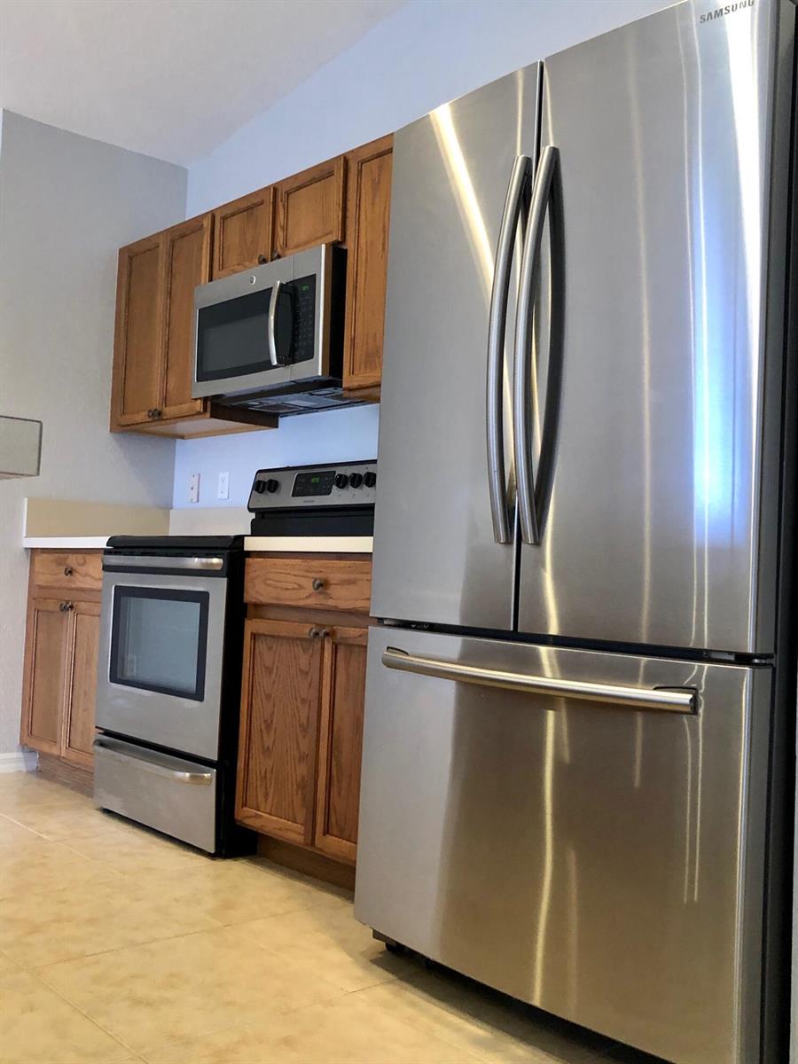 A kitchen features stainless steel appliances, oak cabinets, and light-colored tile flooring — 4801 SE Graham Drive, Stuart FL 34997, STUART, FL