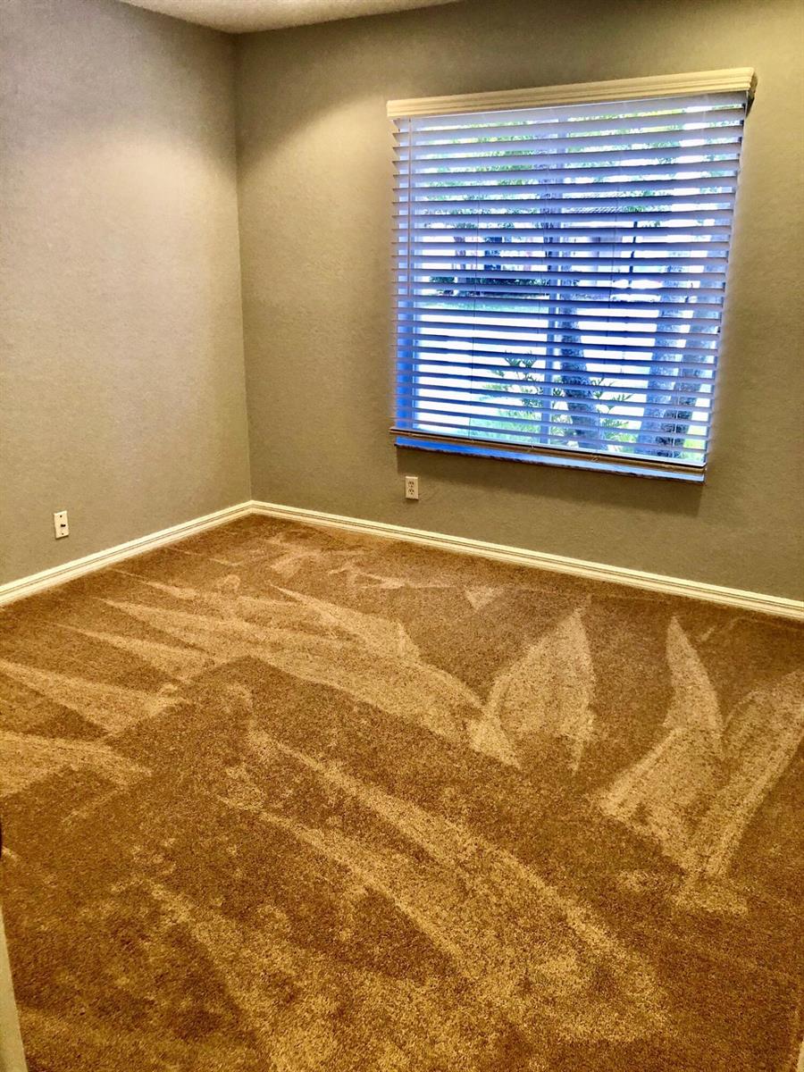An empty bedroom features tan carpet, gray walls, and a window with white horizontal blinds — 4801 SE Graham Drive, Stuart FL 34997, STUART, FL
