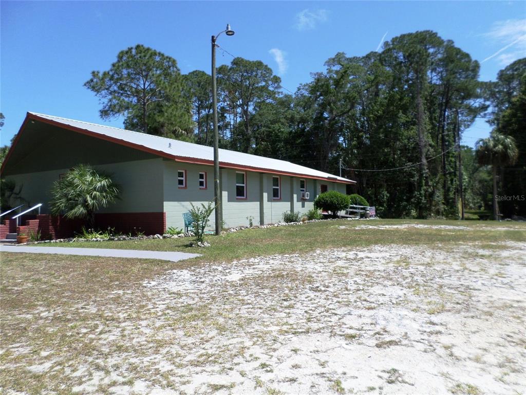 A long, single-story building with light green siding and a metal roof sits on a lot — 6005 HIGHWAY 40 W, YANKEETOWN, FL