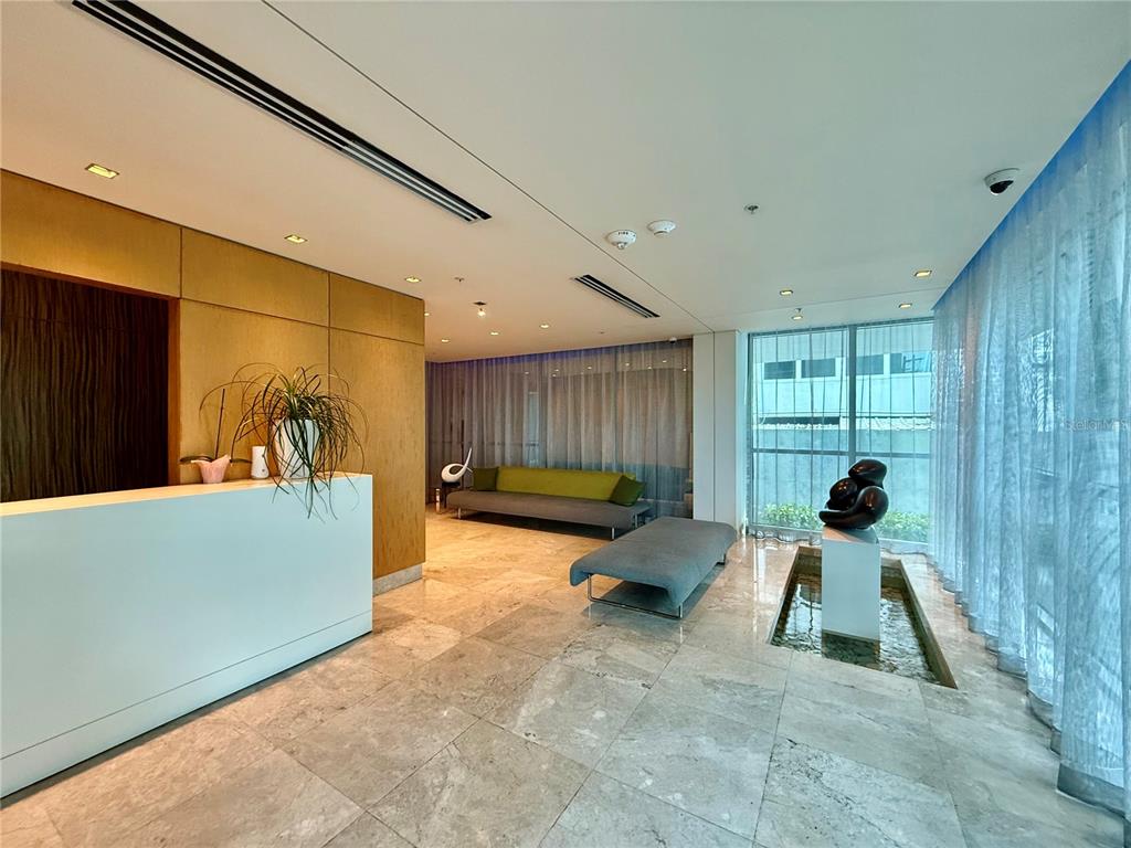 A modern lobby features a white reception desk, marble flooring, seating, and a water feature — 7 C.  MANUEL RODRIGUEZ SERRA UNIT 9, SAN JUAN, PR