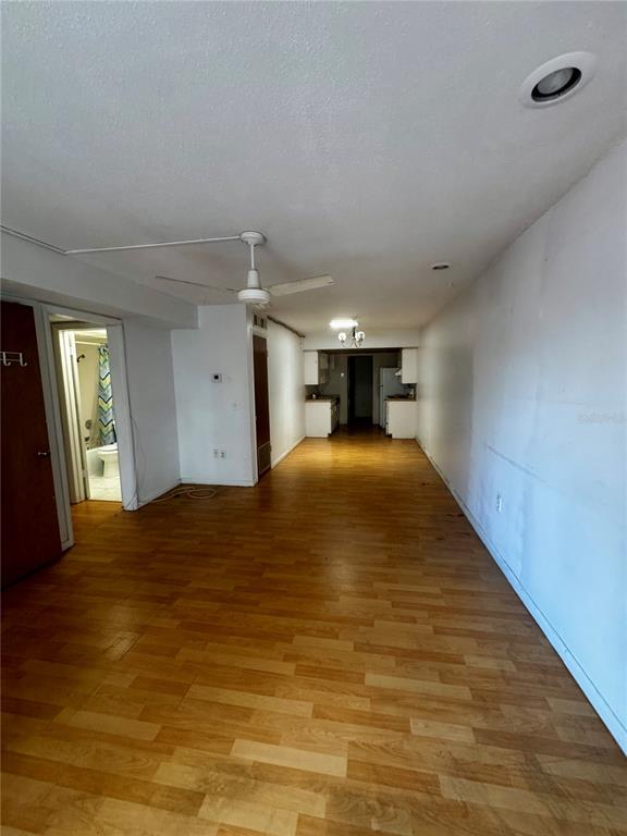 A long, open-concept living area features wood-look flooring, a ceiling fan, and a distant kitchen — 2929 W OAK RIDGE ROAD UNIT F4, ORLANDO, FL
