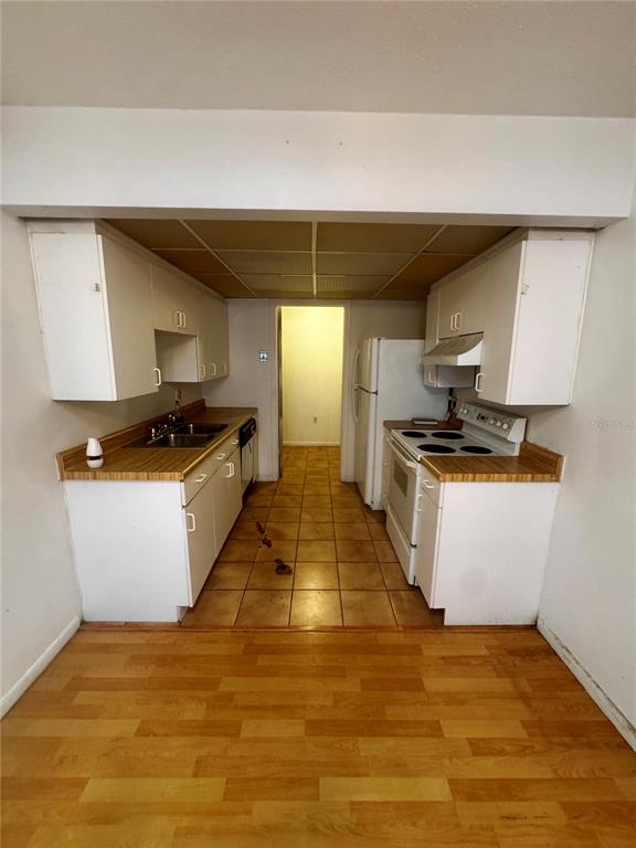A kitchen features white cabinets, wood-look countertops, a white stove, and a tiled floor — 2929 W OAK RIDGE ROAD UNIT F4, ORLANDO, FL