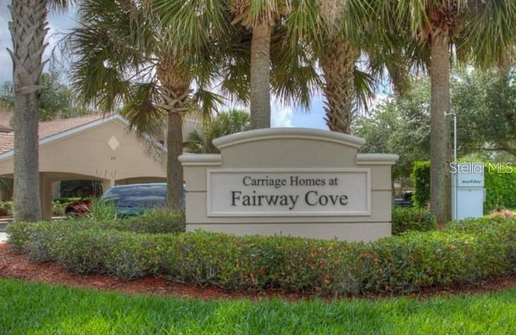 A stone monument sign for Carriage Homes at Fairway Cove stands before palm trees — 803 FAIRWAYCOVE LANE UNIT 204, BRADENTON, FL