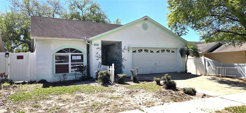 A single-story house with a white exterior, a two-car garage, and a fenced front yard — 2115 INTERVISTA LANE, VALRICO, FL