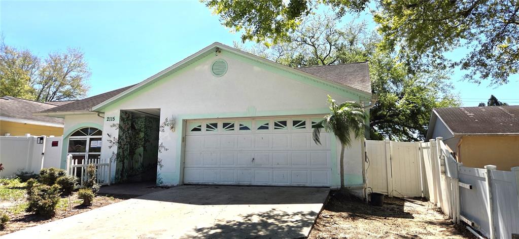 The exterior of a single-story house features a white garage, a side entrance, and fencing — 2115 INTERVISTA LANE, VALRICO, FL