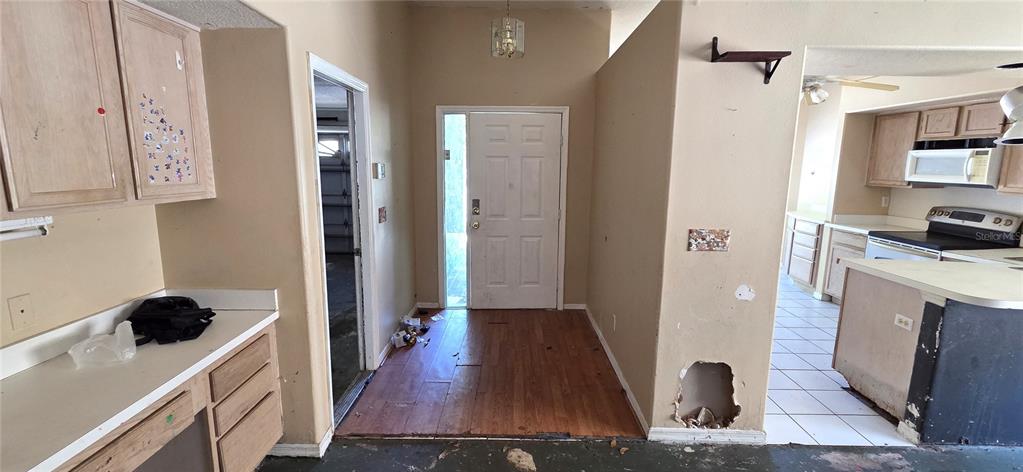 A view of an entryway with wood flooring, a white front door, and adjacent kitchen — 2115 INTERVISTA LANE, VALRICO, FL