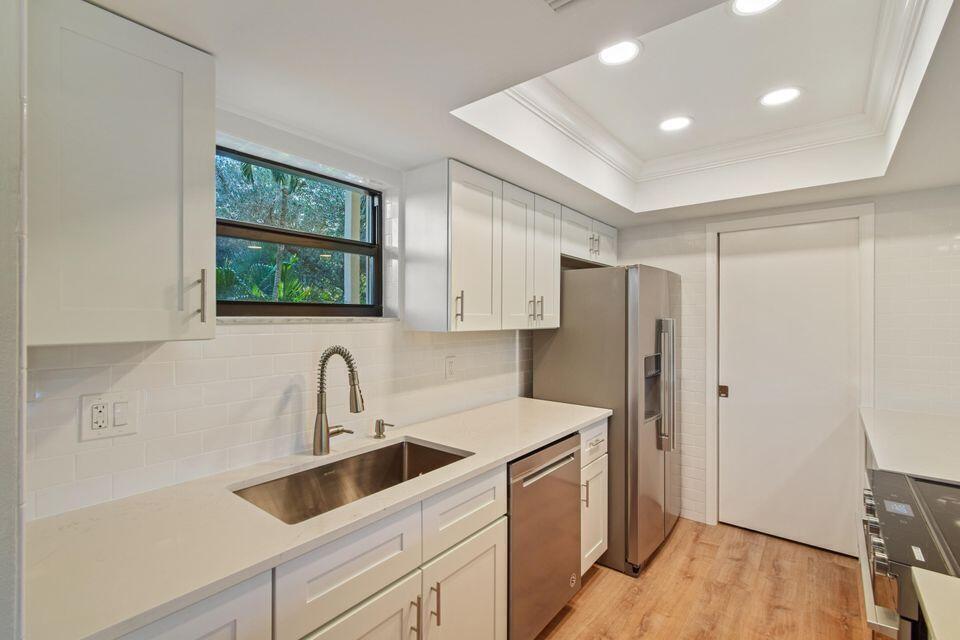 A modern kitchen with white cabinets, stainless steel appliances, and a stainless steel sink — 11863 Wimbledon Circle # 509, Wellington FL 33414, WELLINGTON, FL