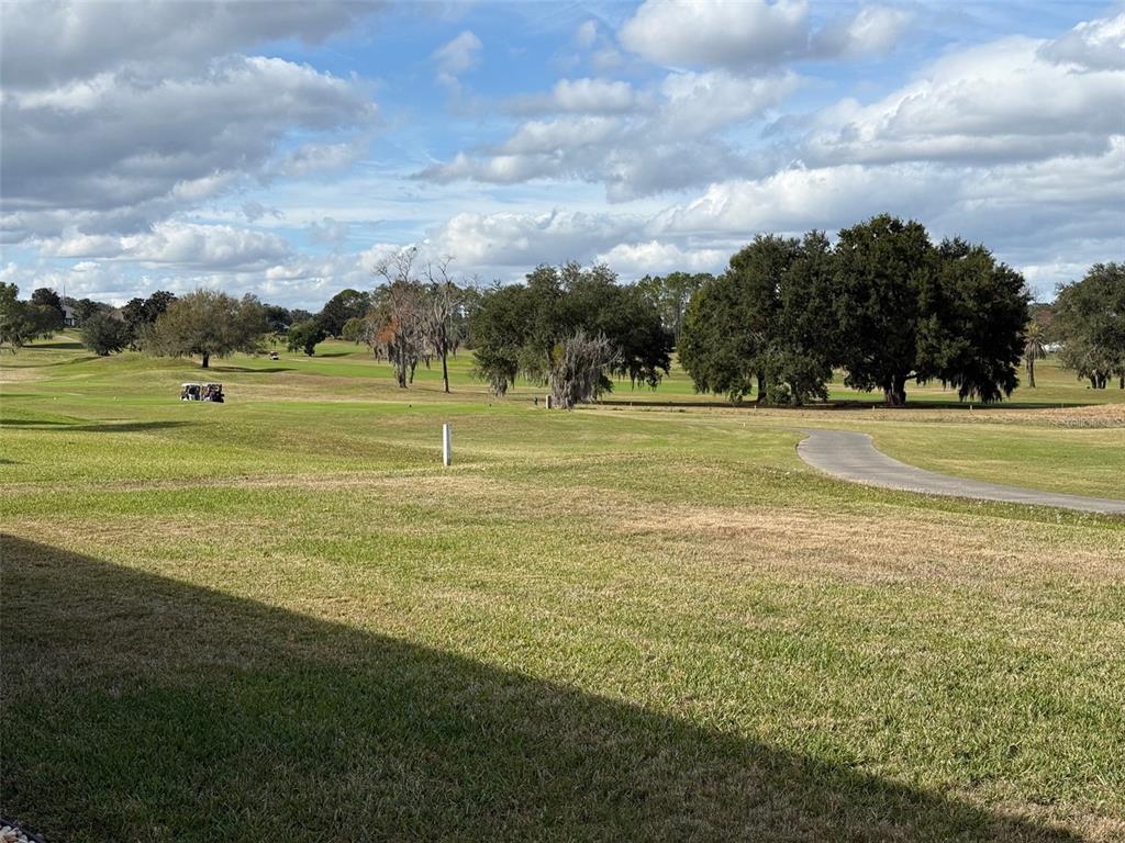 A view of a grassy golf course with trees and a paved cart path — 9685 SE 136TH PLACE, SUMMERFIELD, FL