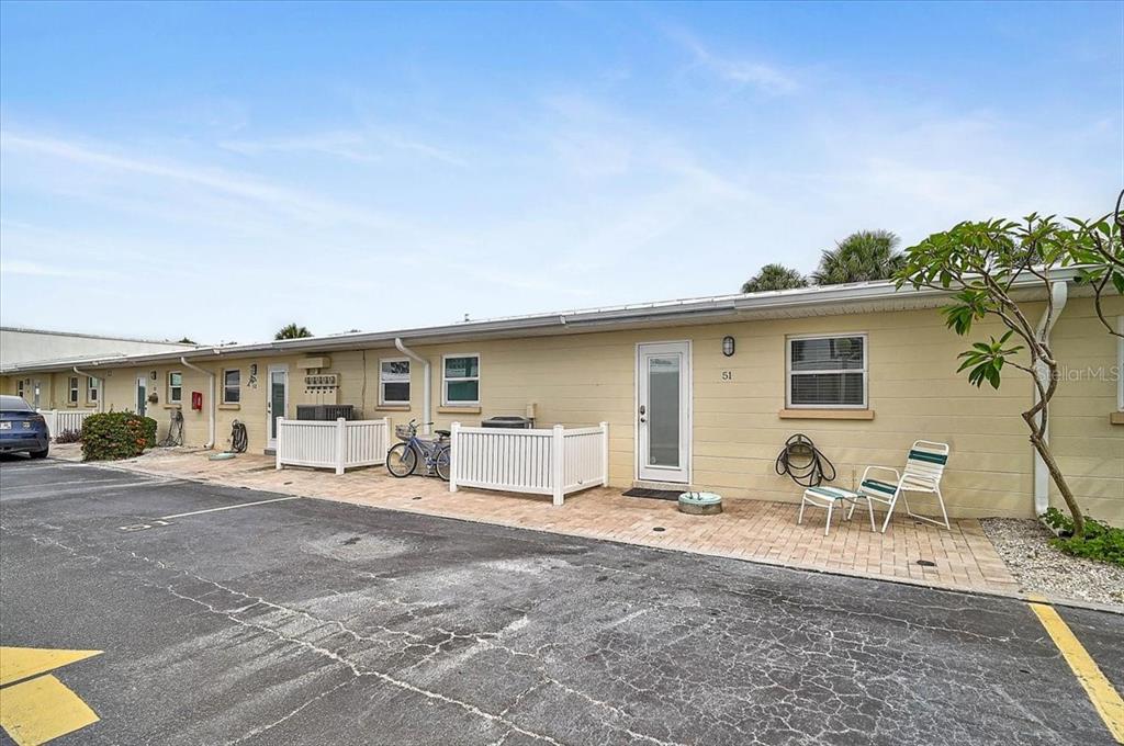 A single-story building with a paved patio, white fencing, and a parking area in front — 5830 MIDNIGHT PASS ROAD UNIT 51, SARASOTA, FL
