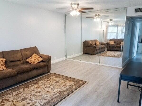 A living room features a brown sofa, a patterned area rug, and a mirrored wall — 25 Upminster B # 25, Deerfield Beach FL 33442, DEERFIELD BEACH, FL