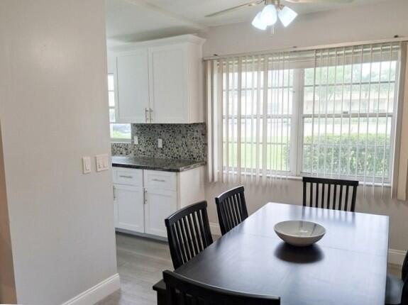 A dining area with a dark table and chairs sits adjacent to a white kitchen — 25 Upminster B # 25, Deerfield Beach FL 33442, DEERFIELD BEACH, FL