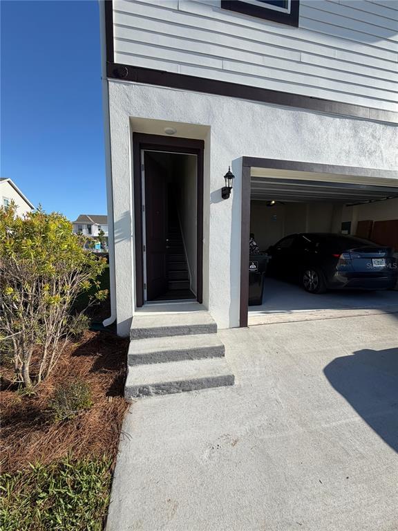 A ground-level view shows a concrete driveway, three steps leading to an entryway, and a garage — 10373 ROSTAND ALLEY ST STREET, ORLANDO, FL