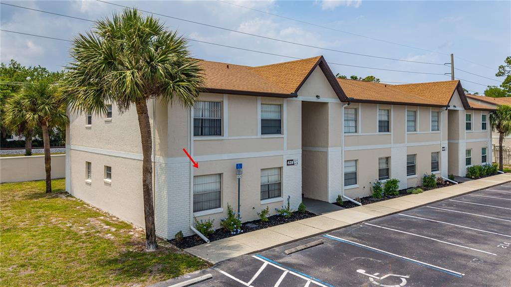 An exterior view of a two-story apartment building with a red arrow pointing to a window — 428 BANANA CAY DRIVE UNIT A, SOUTH DAYTONA, FL
