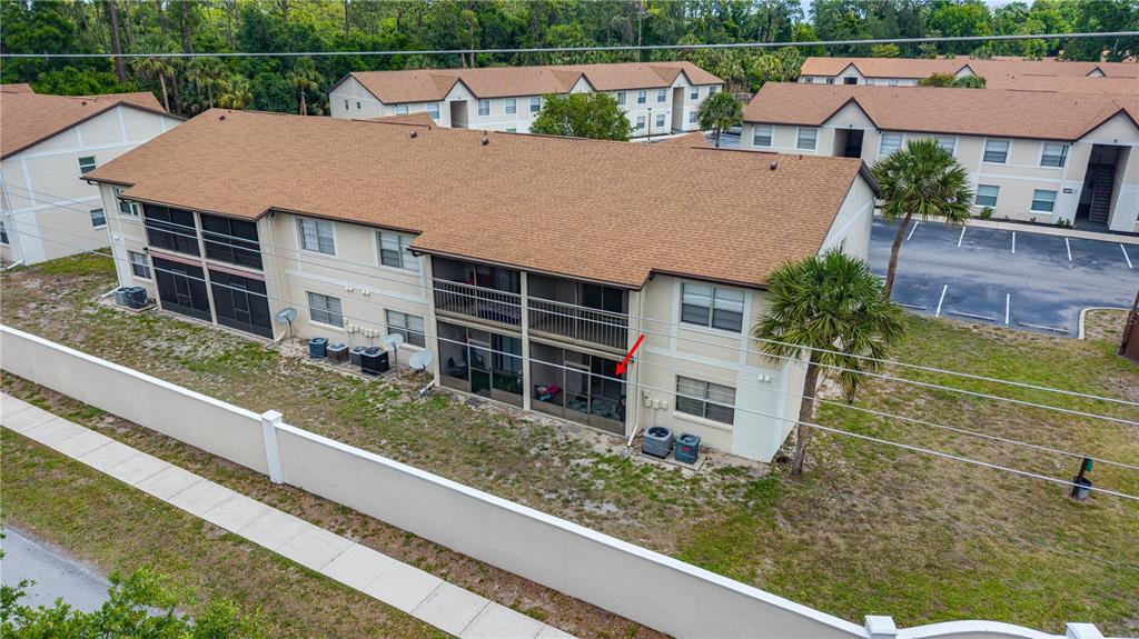 An aerial view of a multi-story apartment building with screened balconies and a perimeter wall — 428 BANANA CAY DRIVE UNIT A, SOUTH DAYTONA, FL