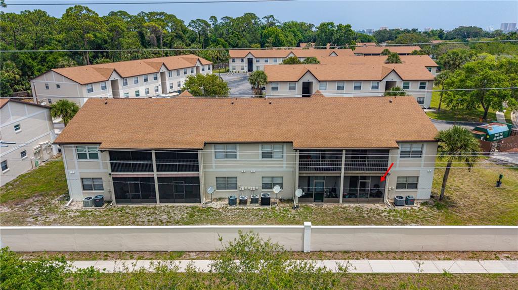 An aerial view of a two-story apartment building with screened-in balconies and a red arrow — 428 BANANA CAY DRIVE UNIT A, SOUTH DAYTONA, FL